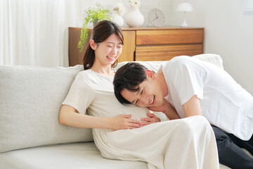 妊娠中の妻のお腹に耳を当てる夫