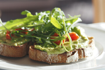 Fresh avocado toast topped with arugula and tomatoes
