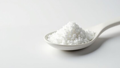 Spoonful of white sugar against white backdrop, granular, white, texture