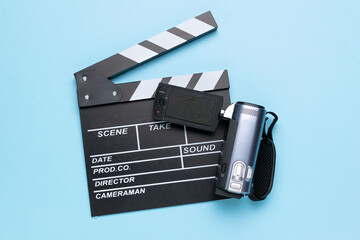 Film Slate and Camcorder on Light Blue Background Reflecting Modern Filmmaking
