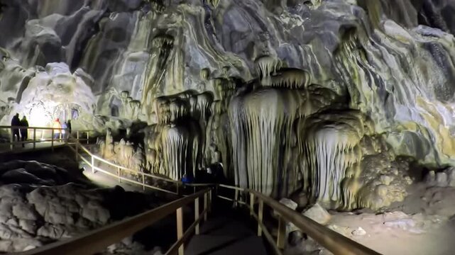 Illuminated cave interior featuring rock formations and a wooden walkway