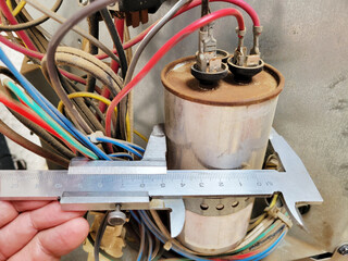 Air conditioner dual-run capacitor diameter measured with a classic caliper, close up