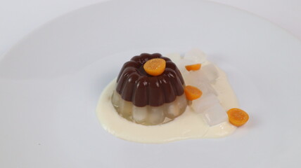 chocolate coconut pudding on a white plate with small orange fruit topping