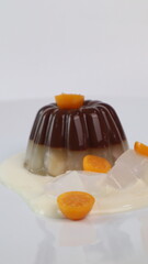 chocolate coconut pudding on a white plate with small orange fruit topping