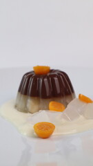 chocolate coconut pudding on a white plate with small orange fruit topping