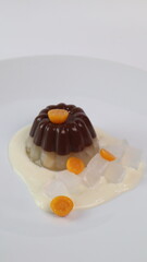 chocolate coconut pudding on a white plate with small orange fruit topping