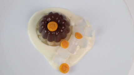 chocolate coconut pudding on a white plate with small orange fruit topping