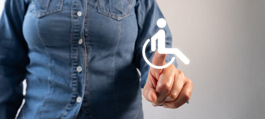 Fototapeta premium Person pointing at an icon toward a floating illuminated wheelchair symbol, representing a balanced environment for people of all abilities.