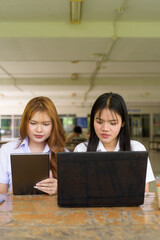 Young Thai University Students Relaxing Together at Campus Cafe Outdoors Using Technology