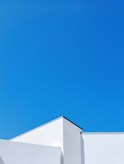 Minimalist architecture: white building corner meets vibrant blue sky in a modern design.