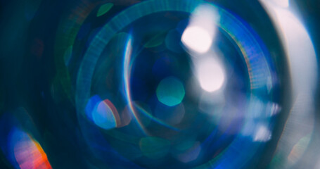 Light circle. Bokeh ray. Defocused green blue colorful sparkling optical round lens flare moving on abstract dark black background.
