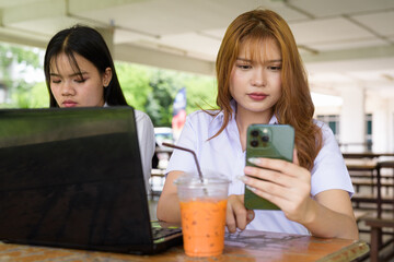 Young Thai University Students Relaxing Together at Campus Cafe Outdoors Using Technology