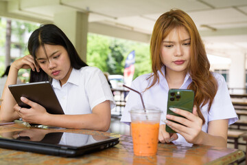 Young Thai University Students Relaxing Together at Campus Cafe Outdoors Using Technology