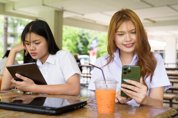 Young Thai University Students Relaxing Together at Campus Cafe Outdoors Using Technology