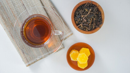 Top view of a clear glass cup of tea with ground tea leaves and sugar cubes isolated on white...