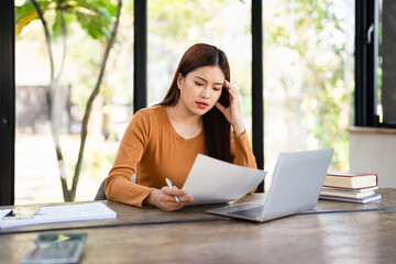  Focused young asian woman looking through paper documents, managing business affairs, summarizing...