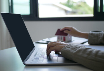 A young woman real estate service worker is sitting at a computer searching for information and...