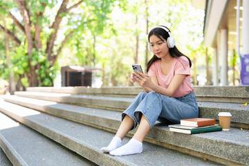 Smiling student   listening to favorite radio station  holding smart phone on steps in campus.