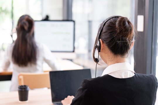 Rear view of woman call center with head set working in team office