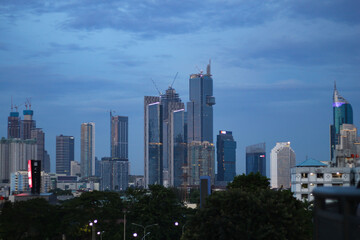 Fototapeta premium A high resolution image of modern skyscrapers and office towers in Jakarta central business district, Indonesia. The photo showcases glass covered buildings under a dramatic cloudy sky, representing t