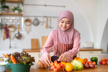 Muslim woman wearing hijab preparing fresh vegetables and fruits in kitchen, healthy lifestyle...