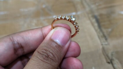 Engagement Ring with Small Diamonds, Held by Hand, Close-up on Rose Gold Ring with Sparking Stones, Ring on Person's Hand, Diamonds Detail