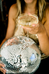 Woman holding disco ball and drinking cocktail at party