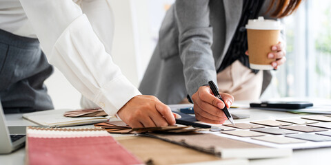 Close up on hands of Interior design, two working colleagues designers, or decorator and client choosing finishing material , women discussing about material samples.