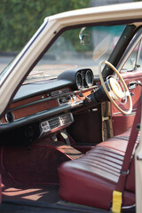 The dashboard of a vintage classic car features detailed analog gauges, a radio, and air vents in...
