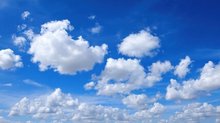 Fototapeta premium White fluffy clouds float lazily across a vibrant blue sky, creating a tranquil atmosphere on a sunny afternoon. The scene evokes a sense of calm and serenity.