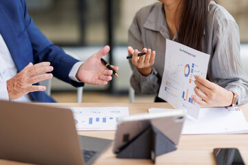 Group of confident business people point to graphs and charts to analyze market data, balance...