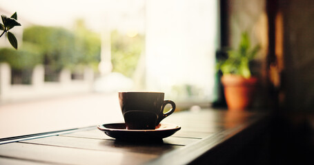 Coffee shop, table and cup by window in cafe for service with beverage, cappuccino and tea. Background, hospitality and mug on counter in restaurant, diner and small business for caffeine drink