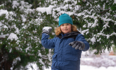 Kid play with snow in winter park. Winter kids with first snow. Child winter holiday. Smiling boy...