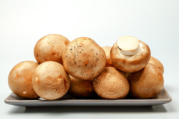 Fresh royal brown mushrooms are presented on a gray rectangular plate, ready for cooking