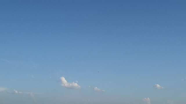 three small white clouds in a huge blue sky fight for life and disappear, dissolving in the sky on a sunny summer day