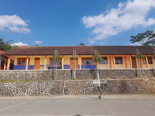 A simple school building in the village, with a tennis court in front of it. The atmosphere is...
