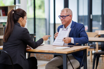 Mature manager Male insurance agent showing place for signature on paper contract document to client.
