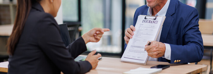 Mature manager Male insurance agent showing place for signature on paper contract document to...