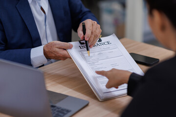 Mature manager Male insurance agent showing place for signature on paper contract document to...