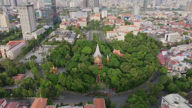 Aerial video of Phnom Penh looks down on Wat Phnom, surrounded by lush trees and government buildings, with the city stretching beyond.