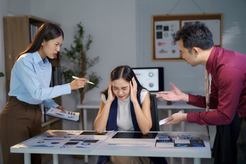 Asian businesspeople are blaming their colleague for bad work results, making her feel stressed and...