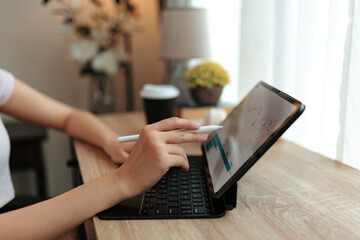 Businesswoman is working with stylus pen and digital tablet, analyzing financial charts, graphs and data, developing marketing strategy and investment plan, working remotely in home office