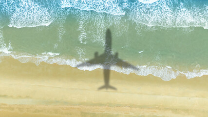 Aerial view of shadow passenger plane silhouette and sandy beach blue sea with waves at sea beach summer vacation sea travel concept	