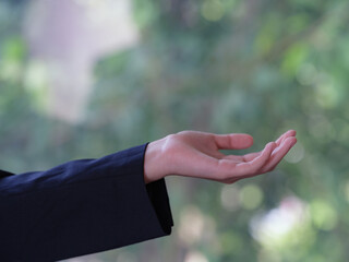 An empty woman's hand holding onto a green natural background.