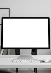 Fototapeta premium Minimalist workspace featuring a blank computer screen, keyboard, and mouse on a white desk.