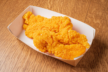 Deliciously fried chicken tenders are arranged neatly in a takeout container, ready to enjoy