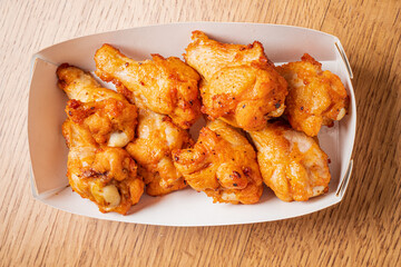 A delicious array of golden crispy chicken wings nestled in a takeout box, ideal for sharing