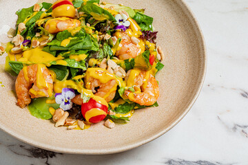 Juicy shrimp on greens with mango dressing and edible flowers for a tasty adventure
