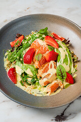 A vibrant salad featuring tender salmon, strawberries, and a rich dressing, artfully presented