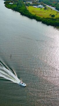 Few motor boats are on the water. Drone footage descending above the river on sunny day. Vertical video